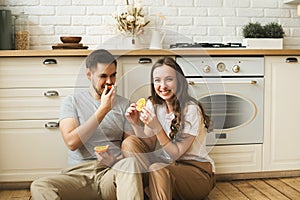 Lifestyle consept at home with couple young men and woman sitting on the floor with slice of orange