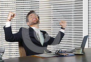 Lifestyle corporate company portrait of young happy and successful business man working excited at modern office sitting by window