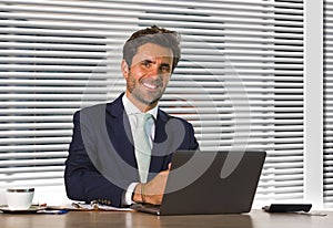 Lifestyle corporate company portrait of young happy and successful business man working relaxed at modern office sitting by window