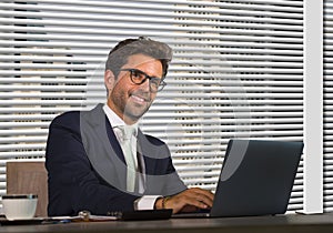 Lifestyle corporate company portrait of young happy and successful business man working relaxed at modern office sitting by window