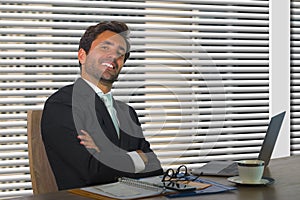 Lifestyle corporate company portrait of young happy and successful business man working relaxed at modern office sitting by window