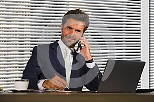 Lifestyle corporate company portrait of young happy and successful business man working relaxed at modern office sitting by window