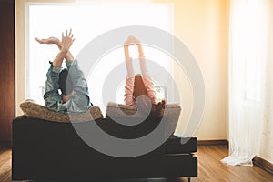 Lifestyle Couple in love and relaxing on a sofa at home and looking outside through the window of the living room.