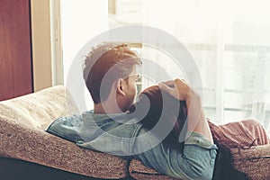 Lifestyle Couple in love and relaxing on a sofa at home and looking outside through the window of the living room, sunny day.