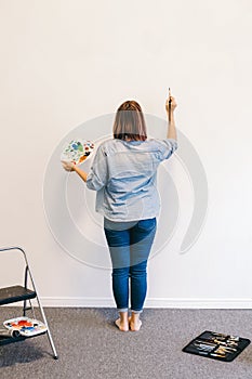 Lifestyle creative hobby and freelance artistic work side job concept. Caucasian woman artist hand painting murals on walls indoor