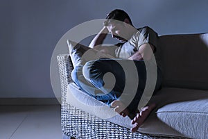 Lifestyle dramatic light portrait of young sad and depressed man sitting at shady home couch in pain and depression feeling lost l