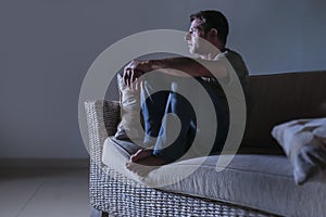 Lifestyle dramatic light portrait of young sad and depressed man sitting at shady home couch in pain and depression feeling lost l