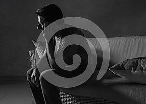 Lifestyle dramatic light portrait of young sad and depressed man sitting at shady home couch in pain and depression feeling lost l