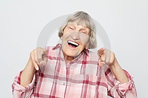 Lifestyle, emotion and people concept: Aged grandmother with shocked face. Portrait of grandmother with pink shirt.