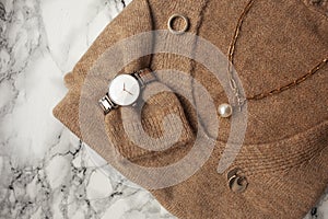 Lifestyle and fashion flat lay: clothes and rose gold jewelry on marble background