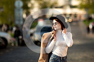 Lifestyle fashion portrait of young stylish hipster woman walking on the street.