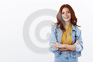 Lifestyle, fashion and women concept. Cheerful ambitious redhead woman in denim jacket cross arms in confident pose