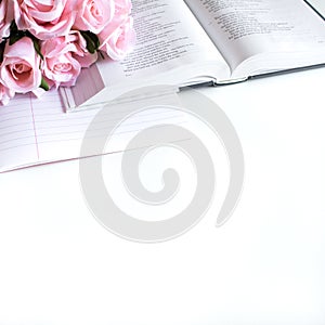 Flat lay with different accessories; flower bouquet, pink roses, open book, Bible