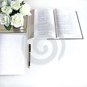 Flat lay with different accessories; flower bouquet, pink roses, open book, Bible