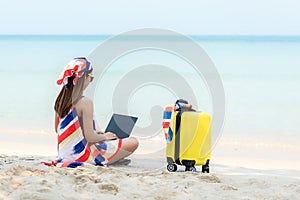 Lifestyle freelance woman using laptop working on the beach.