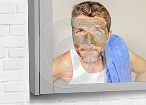 Lifestyle funny portrait of young attractive and surprised man horrified looking himself on bathroom mirror ugly and weird face ap