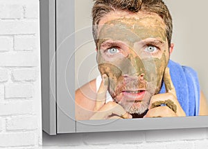 Lifestyle funny portrait of young attractive and surprised man horrified looking himself on bathroom mirror ugly and weird face ap