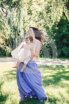 Lifestyle group portrait of smiling white Caucasian brunette mother holding hugging daughter in pink dress dancing