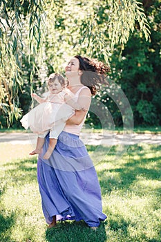 Lifestyle group portrait of smiling white Caucasian brunette mother holding hugging daughter in pink dress dancing