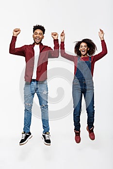 Lifestyle ,happiness and people concept: Happy young lovely African American couple jumping over bright grey background.