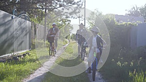 Lifestyle, happy grandchild and his merry grandparents have fun and enjoy a joint ride on bicycles and ride on a rural