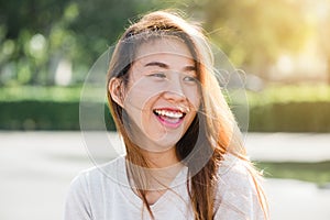 Lifestyle happy young adult asian woman smiling with teeth smile outdoors and walking on city street at sunset time.