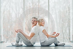 Lifestyle, health and sport concept.Senior couple doing yoga in the class and looking at camera and smiling