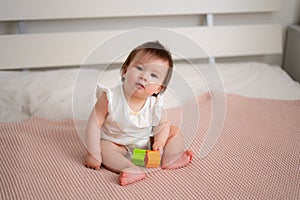 lifestyle home portrait of 9 months old mixed ethnicity Asian Caucasian baby girl playing happy and carefree on bed crawling and