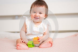 lifestyle home portrait of 9 months old mixed ethnicity Asian Caucasian baby girl playing happy and carefree on bed crawling and