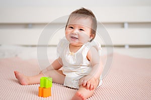 lifestyle home portrait of 9 months old mixed ethnicity Asian Caucasian baby girl playing happy and carefree on bed crawling and