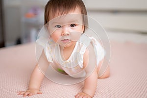 lifestyle home portrait of 9 months old mixed ethnicity Asian Caucasian baby girl playing happy and carefree on bed crawling and