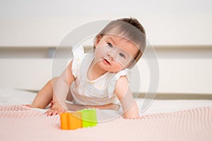 lifestyle home portrait of 9 months old mixed ethnicity Asian Caucasian baby girl playing happy and carefree on bed crawling and