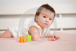 lifestyle home portrait of 9 months old mixed ethnicity Asian Caucasian baby girl playing happy and carefree on bed crawling and