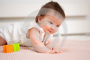 lifestyle home portrait of 9 months old mixed ethnicity Asian Caucasian baby girl playing happy and carefree on bed crawling and