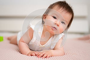 lifestyle home portrait of 9 months old mixed ethnicity Asian Caucasian baby girl playing happy and carefree on bed crawling and