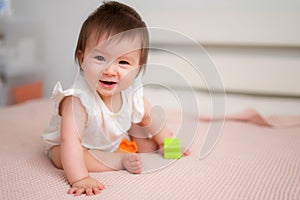 lifestyle home portrait of 9 months old mixed ethnicity Asian Caucasian baby girl playing happy and carefree on bed crawling and