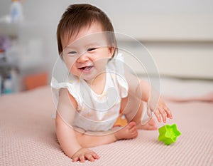 lifestyle home portrait of 9 months old mixed ethnicity Asian Caucasian baby girl playing happy and carefree on bed crawling and