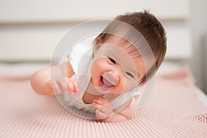 lifestyle home portrait of 9 months old mixed ethnicity Asian Caucasian baby girl playing happy and carefree on bed crawling