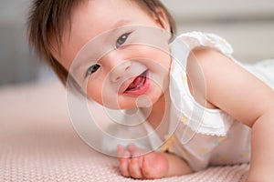 lifestyle home portrait of 9 months old mixed ethnicity Asian Caucasian baby girl playing happy and carefree on bed crawling