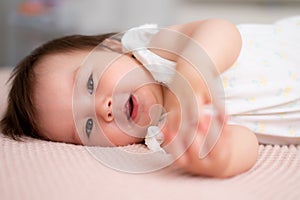 lifestyle home portrait of 9 months old mixed ethnicity Asian Caucasian baby girl playing happy and carefree on bed crawling