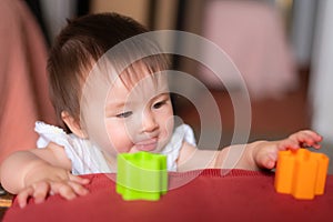 lifestyle home portrait of adorable and beautiful Asian Caucasian mixed baby girl playing on bed with color blocks excited and