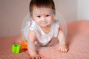 lifestyle home portrait of adorable and beautiful Asian Caucasian mixed baby girl playing on bed with color blocks excited and