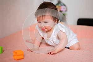 lifestyle home portrait of adorable and beautiful Asian Caucasian mixed baby girl playing on bed with color blocks excited and