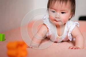 lifestyle home portrait of adorable and beautiful Asian Caucasian mixed baby girl playing on bed with color blocks excited and