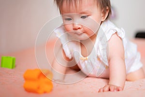 lifestyle home portrait of adorable and beautiful Asian Caucasian mixed baby girl playing on bed with color blocks excited and