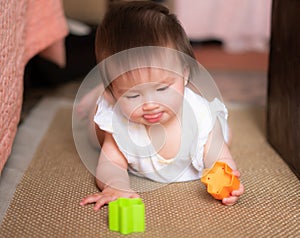 lifestyle home portrait of adorable and beautiful Asian Caucasian mixed baby girl playing on the floor with color blocks excited