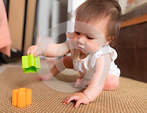 lifestyle home portrait of adorable and beautiful Asian Caucasian mixed baby girl playing on the floor with color blocks excited