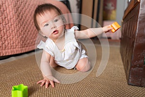 lifestyle home portrait of adorable and beautiful Asian Caucasian mixed baby girl playing on the floor with color blocks excited