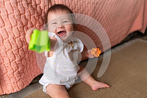 lifestyle home portrait of adorable and beautiful Asian Caucasian mixed baby girl playing on the floor with color blocks excited