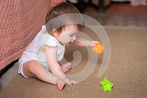 lifestyle home portrait of adorable and beautiful Asian Caucasian mixed baby girl playing on the floor with color blocks excited